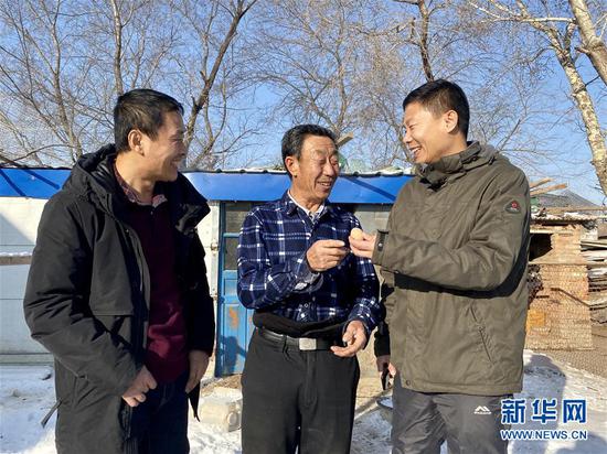黑龙江省大庆市杜尔伯特蒙古族自治县一心乡前进村驻村工作队队长、第一书记慕海军（右）、工作队队员韩明祥（左）和69岁的脱贫户杨双交流（2020年1月4日摄）。新华社记者 杨思琪 摄