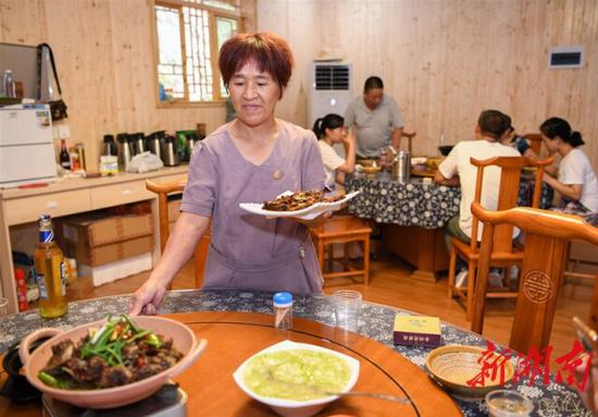 （8月12日，沅陵县官庄镇界亭驿村金州湾驿站，黄三妹在为客人上菜。）