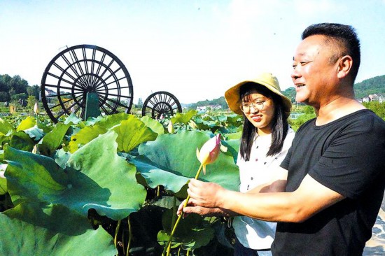 罗河镇鲍店村党组织负责人汪海洋（右）向游客介绍景区的看点。.jpg