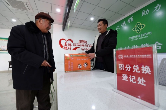在安徽省滁州市凤阳县小岗村,村民缪守鲁(左)在村里“美德银行”用积分兑换生活物品(2021年1月30日摄)。新华社记者 周牧 摄